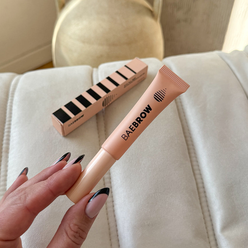 Brow gel with 'BAEBROW' branding held by a hand on a light background