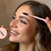 Woman getting her eyebrows done with a BAEBROW brow styling brush